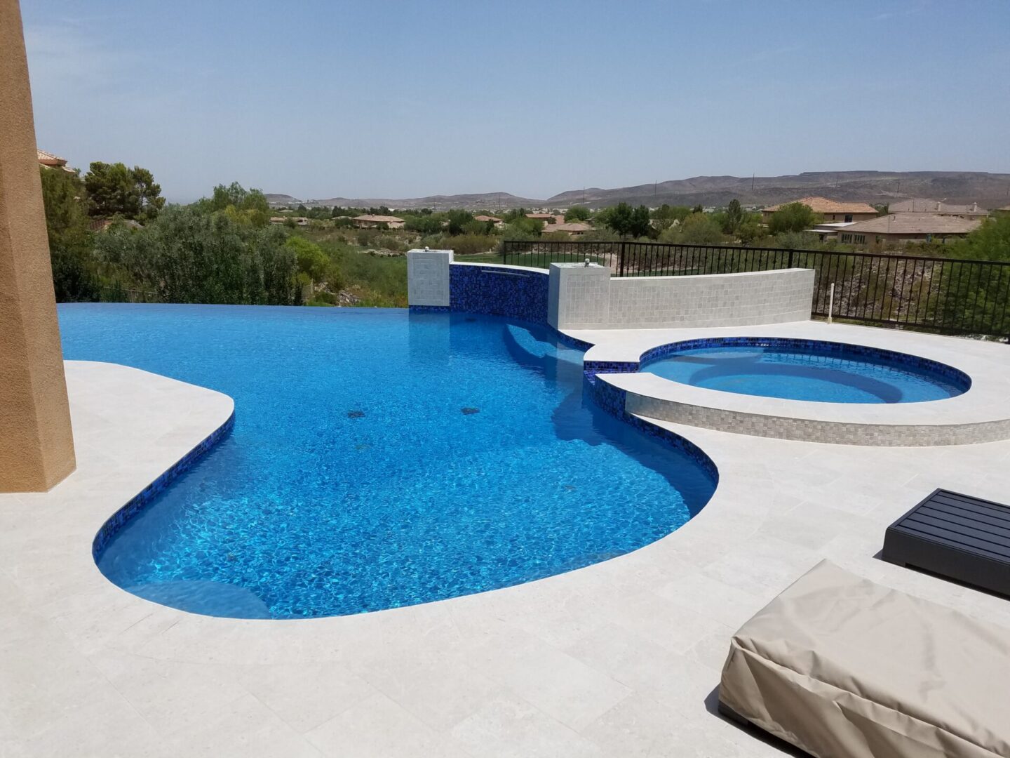 A serene blue swimming pool with a view of distant hills under a clear sky.