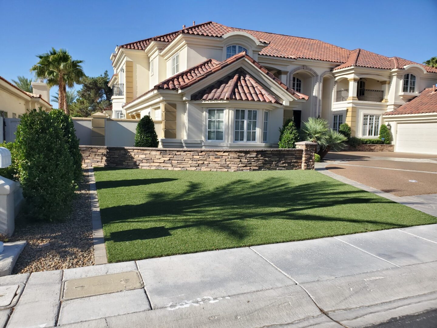 A sunny suburban house with a well-kept lawn and tiled roof.