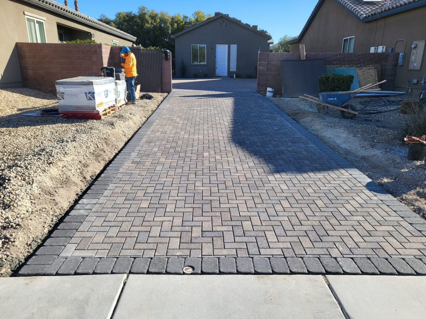 Newly paved brick driveway in a residential area under clear blue sky.