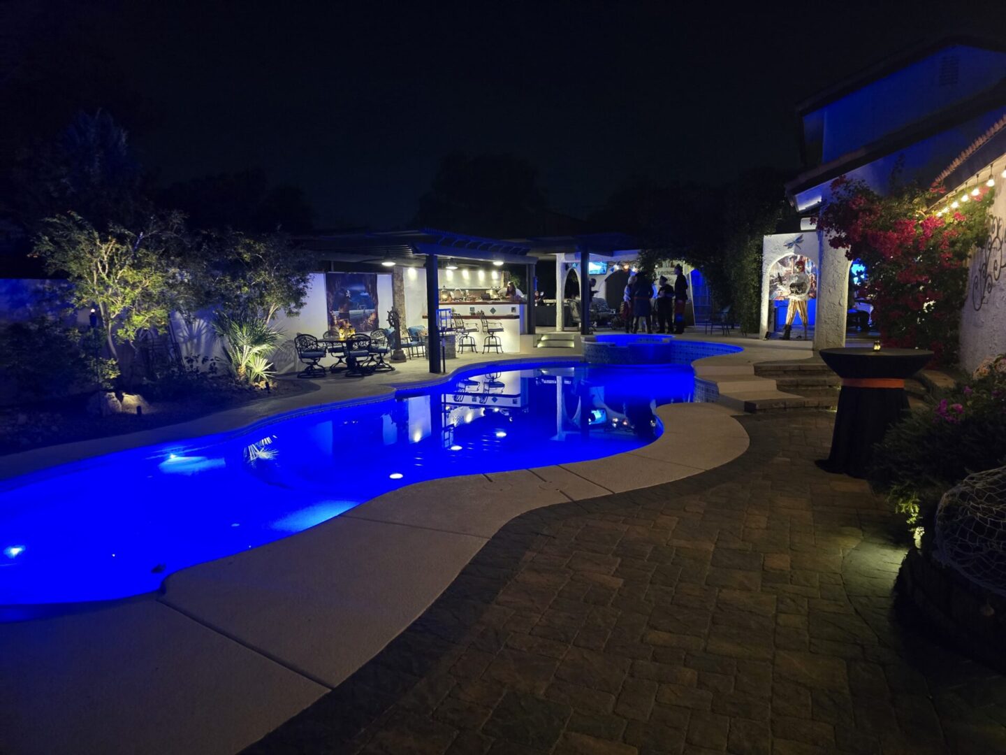 A backyard pool illuminated with blue lights at night.